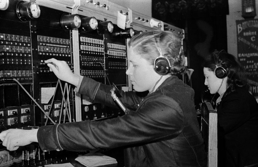 Стахановка-телефонистка городской телефонной станции А.П. Королева. 1942 г. Российский государственный архив кинофотодокументов. Арх. № 0-64318. Автор не установлен. Сайт https://stalingrad.rusarchives.ru/dokumenty/stahanovka-telefonistka-gorodskoy-telefonnoy-stancii-ap-koroleva